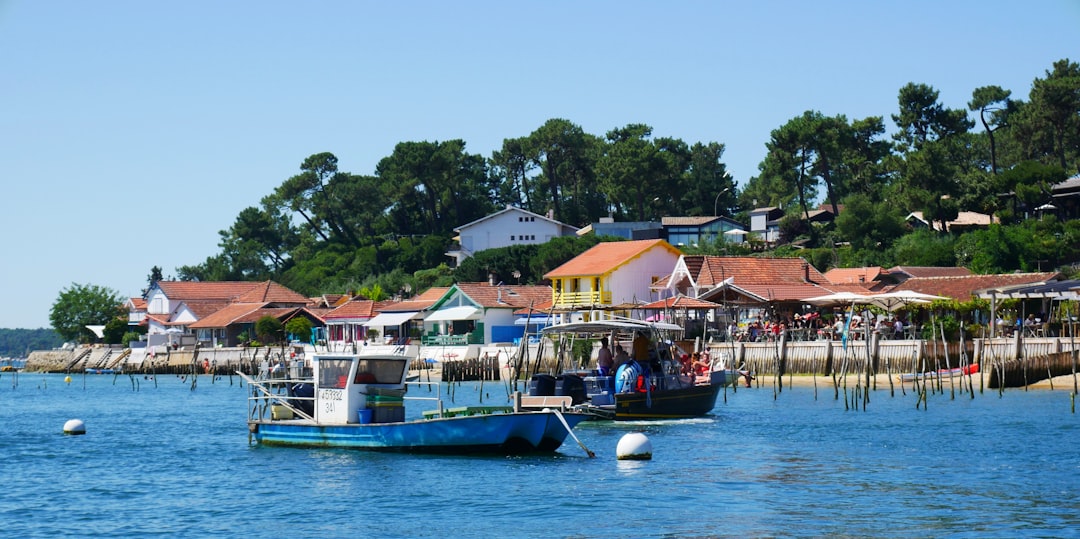 Un village ostréicole du bassin d'Arcachon vu de l'eau, une pinasse bleue au premier plan